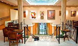 Interiör av en elegant byggnad med konstverk på väggarna och sittplatser runtom. (AI-genererad text)