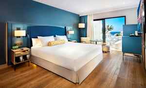 Hotellrum med dubbelbädd, sittmöbler och utsikt mot havet. (AI-genererad text)