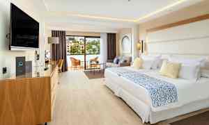 Ett hotellrum med två sängar, sittgrupp och balkong. (AI-genererad text)