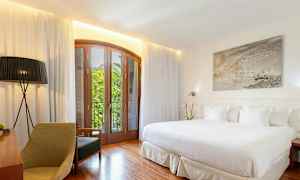 Ett ljust hotellrum med en stor säng, trädetaljer och en balkong med utsikt. (AI-genererad text)