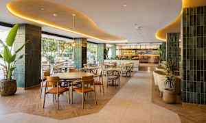 En elegant restaurang med moderna möbler och inredning, belägen inomhus med gröna detaljer och stor bar i bakgrunden. (AI-genererad text)