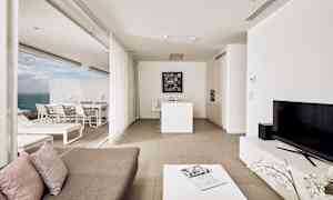 En modern lägenhet med öppen planlösning, ljus inredning och utsikt mot havet. (AI-genererad text)