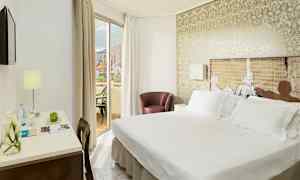 Ett hotellrum med dubbelsäng, ett skrivbord med lampa och en balkong med utsikt. (AI-genererad text)