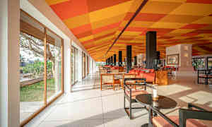 Ett ljust och rymligt rum med glasväggar, färgglatt rutmönster på taket, och moderna sittmöbler. (AI-genererad text)