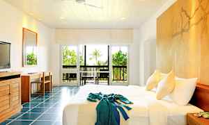 Ett ljust hotellrum med en stor säng, vita väggar och fönster som vetter mot en grönskande trädgård. (AI-genererad text)