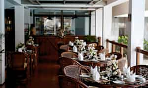 En restaurang med dukade bord och blommor på varje bord. (AI-genererad text)