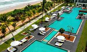 Ett poolområde vid en strand med solstolar och parasoller. (AI-genererad text)