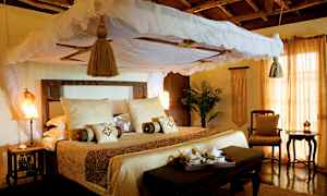 En inbjudande säng med baldakin och ljusa textilier i ett rustikt inrett rum. (AI-genererad text)