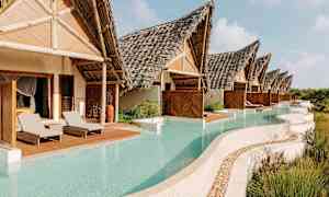 Bilden visar en rad av villor med halmtak, som har privata pooler framför, omgivna av vegetation. (AI-genererad text)