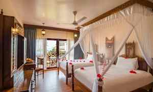 Hotellrum med två sängar, dekorerade med myggnät och röda blomblad. (AI-genererad text)