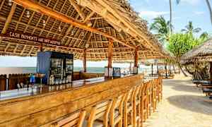 Strandbar med träbord och stolar under tak av palmblad. (AI-genererad text)