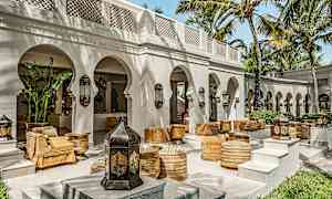 En utomhusterrass med valv, palmer och sittplatser inspirerade av arabisk design. (AI-genererad text)