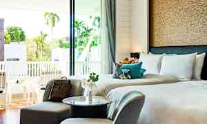 Hotellrum med dubbelsäng, sittgrupp och balkong med utsikt. (AI-genererad text)