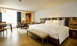 Modernt hotellrum med en stor säng, sittgrupp och arbetsbord. (AI-genererad text)