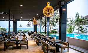 En restaurang med sittplatser utomhus vid en pool, med havet i bakgrunden. (AI-genererad text)