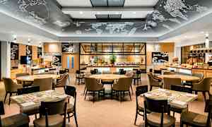 En modern restauranginredning med bord och stolar samt en serveringsbuffé i bakgrunden. (AI-genererad text)