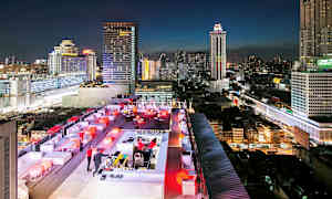 En takbar med belysning under kvällen och en stadsmiljö fylld med höga byggnader i bakgrunden. (AI-genererad text)