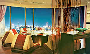 En elegant matsal med panoramautsikt över en upplyst stad på kvällen. (AI-genererad text)