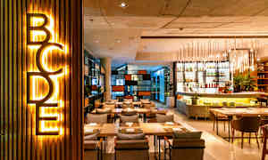 Ett modernt restaurangområde med belysning, sittplatser och en bardisk. (AI-genererad text)