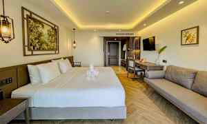 Modernt inrett hotellrum med dubbelsäng, soffa och arbetsyta. (AI-genererad text)