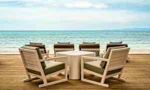 Trämöbler på en terrass med utsikt över havet. (AI-genererad text)