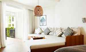 Ett vardagsrum med en hörnsoffa, kuddar och glasdörrar som leder till en uteplats. (AI-genererad text)