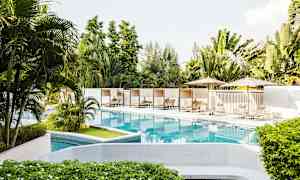 Poolområde med solsängar och parasoller omgivna av grönska. (AI-genererad text)