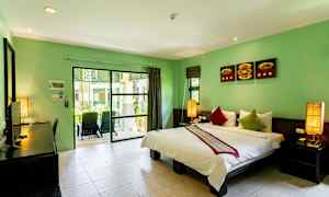Ett hotellrum med dubbelsäng och gröna väggar, samt en balkong med utsikt mot grönska. (AI-genererad text)