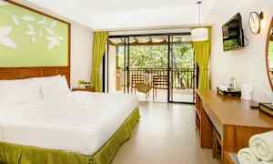 Ett hotellrum med en dubbelsäng, skrivbord och utsikt mot en balkong. (AI-genererad text)