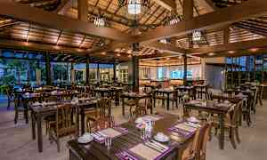 En öppen restaurang med träbord och stolar, dukade för måltider. (AI-genererad text)