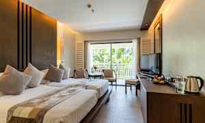 Ett hotellrum med två sängar, en sittgrupp, en balkong och en tv. (AI-genererad text)