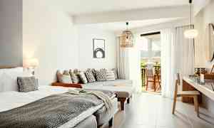 Ljusa och moderna hotellrum med säng, sittmöbler och öppning till balkong. (AI-genererad text)