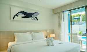 Ett hotellrum med en dubbelsäng, dekorerad med handdukar och en tavla på en val på vägg. Rummet har ett fönster med utsikt mot en pool. (AI-genererad text)