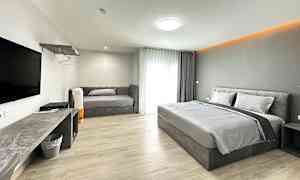 Ett hotellrum med en dubbelsäng, en soffa och en TV på väggen. (AI-genererad text)