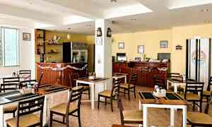 En bild av en liten restaurang eller café med bord och stolar, en bardisk och inredning inklusive prydnadssaker och dekorationer. (AI-genererad text)