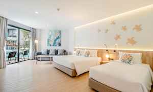 Rum med två sängar, en soffa och ett bord nära ett stort fönster med utsikt. (AI-genererad text)