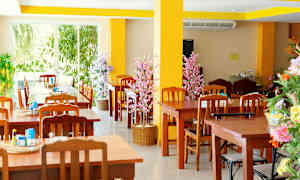 Restaurang med träbord och stolar samt dekorativa blommor. (AI-genererad text)