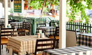 Bild på en restaurang med rutiga dukar och bord representerade utomhus. (AI-genererad text)