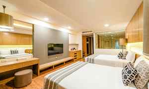 Hotelrum med två bäddar, en TV på väggen och ett glasfönster som vetter mot badrummet. (AI-genererad text)