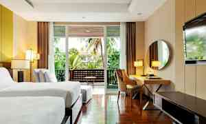 Modernt hotellrum med två enkelsängar, skrivbord, spegel och balkong med grön utsikt. (AI-genererad text)