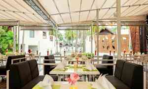 Uteservering med dukade bord och stolar under tak. (AI-genererad text)