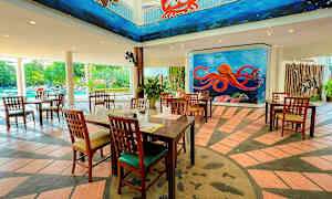 Restaurang med trämöbler, färgglada väggmålningar med havstema, och en pool i bakgrunden. (AI-genererad text)