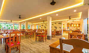 Bild på en ljus restaurang med träbord och stolar. (AI-genererad text)