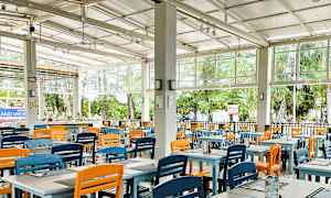 Restaurang med färgglada stolar och öppet till en grönskande utsikt. (AI-genererad text)