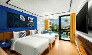 Ett modernt hotellrum med två separata sängar, blå och gula inredningsdetaljer samt en glasdörr som leder ut till en liten terrass och poolområde. (AI-genererad text)