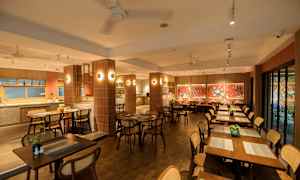 En restaurang med träbord och stolar, dekorerad med röda väggar och konstverk. (AI-genererad text)