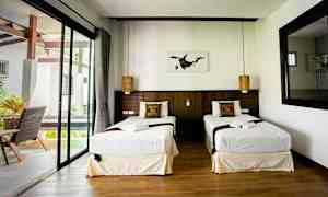 Dubbelrum med två enkelsängar, fönster och dekorerade kuddar. (AI-genererad text)