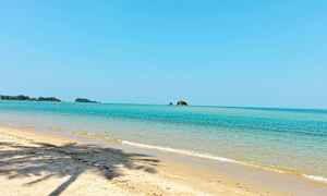 Sandstrand med klart blått hav och några små öar i bakgrunden. (AI-genererad text)