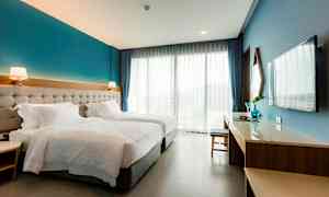 Hotellrum med två enkelsängar, skrivbord, TV och stora fönster. (AI-genererad text)