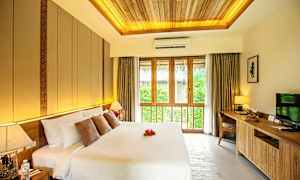 Ett sovrum med en stor dubbelsäng, dekorativa kuddar och sänglampa. Ett stort fönster med gardiner släpper in naturligt ljus. (AI-genererad text)